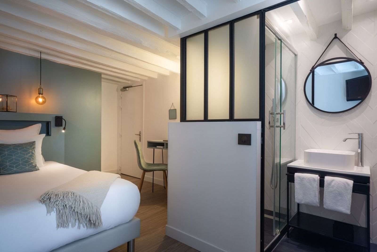 Ein modernes Hotelzimmer mit Bett, Nachttisch und einer Duschkabine aus Glas.