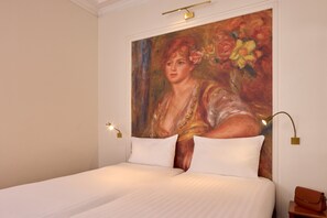 Une chambre d’hôtel avec un grand lit, deux oreillers blancs, un tableau au mur et une table de chevet avec une lampe.