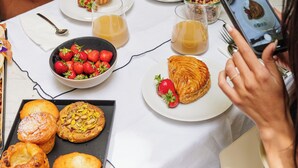 Una mesa de comedor con platos de comida, una vela y un teléfono inteligente.