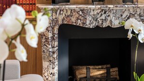 A fireplace with a marble surround, a bookshelf with books, and a wall-mounted candelabra. - Villa Madame (Paris)