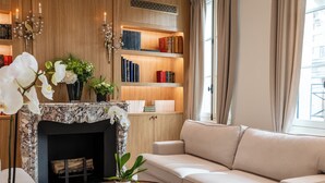 A modern living room with a fireplace, beige sofa, coffee table, and a bookshelf. - Villa Madame (Paris)