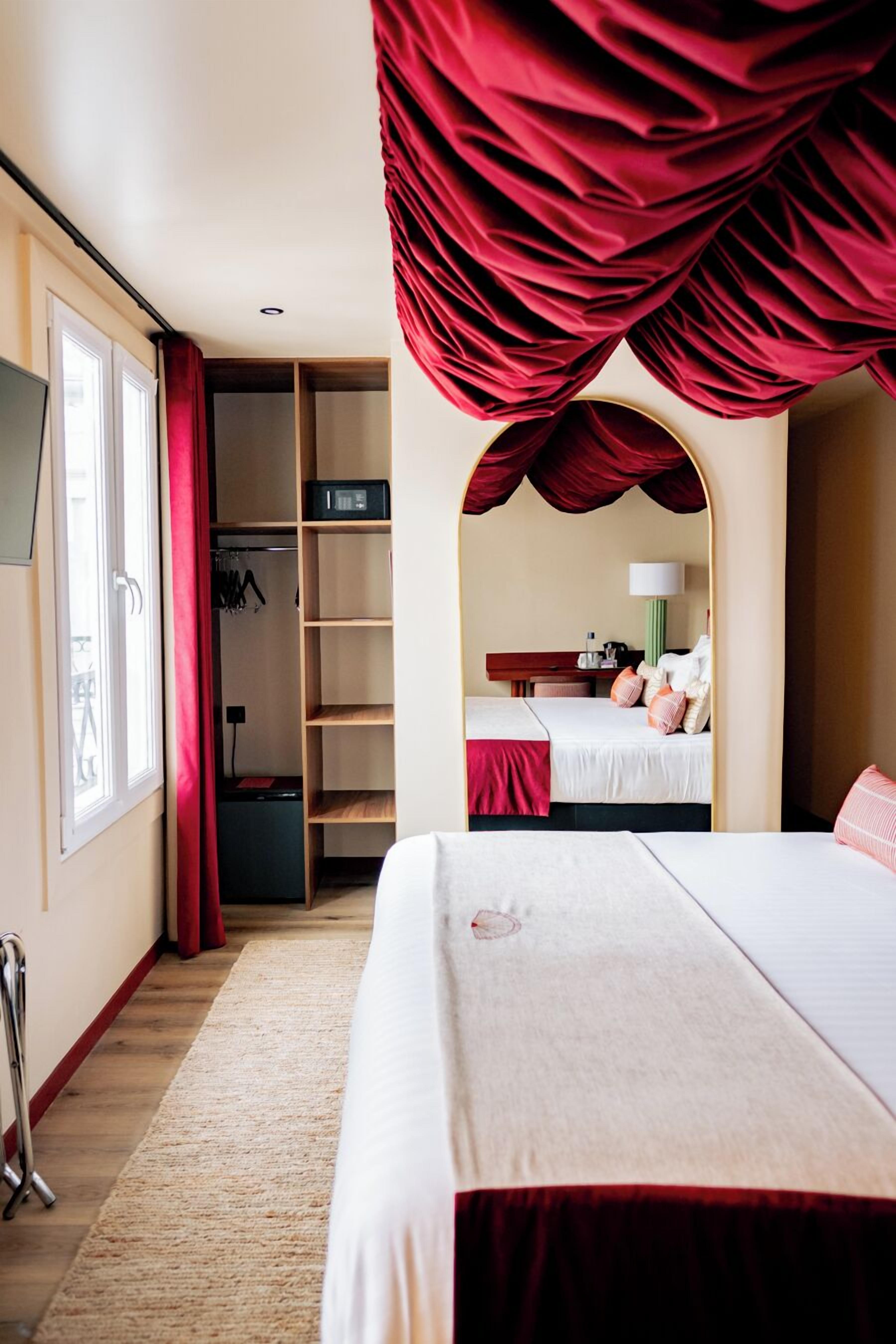 Ett hotellrum med en stor säng, en garderob, en spegel och ett skrivbord.