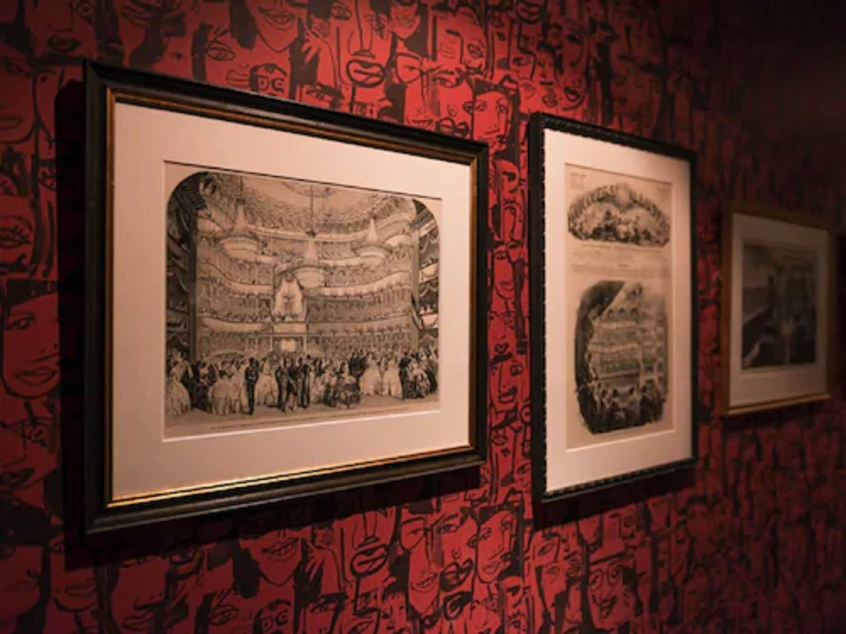A wall with framed black and white photographs of a theater and a crowd.