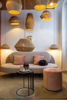 Un salon moderne avec un canapé, un pouf et une petite table sur laquelle se trouvent un verre et un livre.