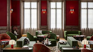 Un salón moderno con sofás verdes, un tapete estampado de leopardo y una araña.
