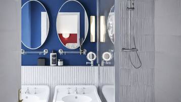 A modern bathroom with three white sinks, a large mirror, and a shower area.