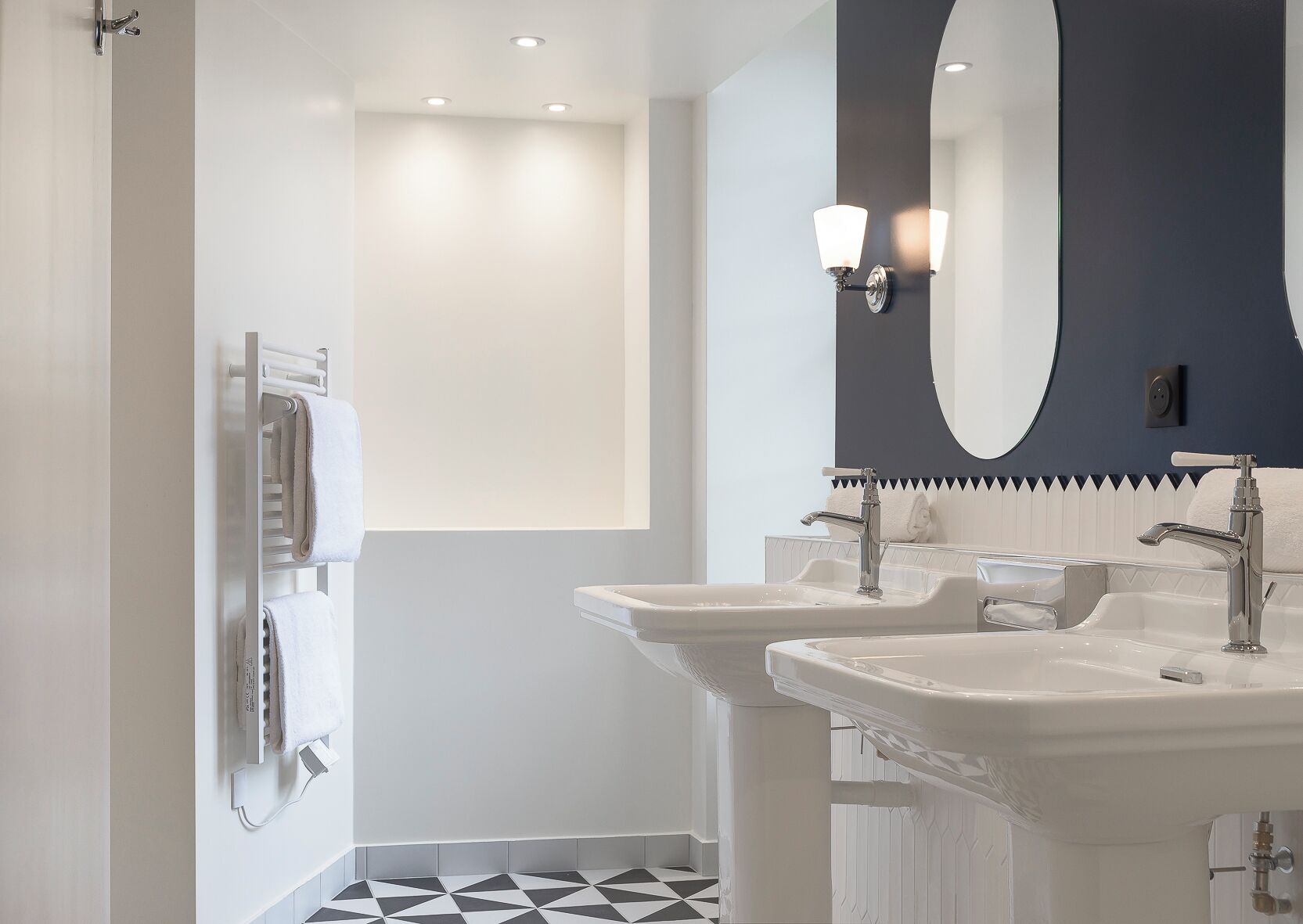 A modern bathroom with two sinks, a large mirror, and a towel rack.