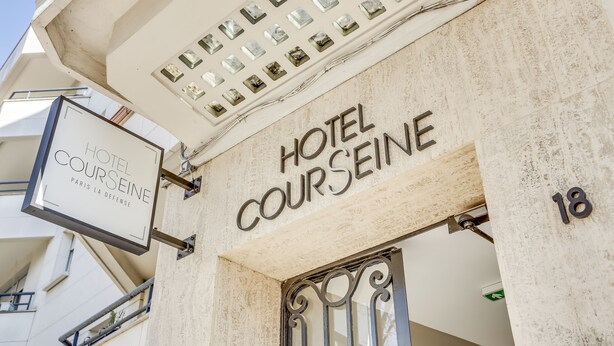 The exterior of Hotel Courseine, featuring a signboard with the hotel's name, a number '18' on the wall, and a metal gate. - Hotel Courseine (Courbevoie)
