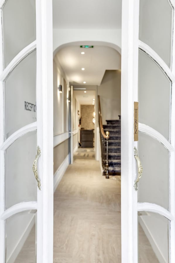 A hotel reception area with a marble staircase and a reception desk.