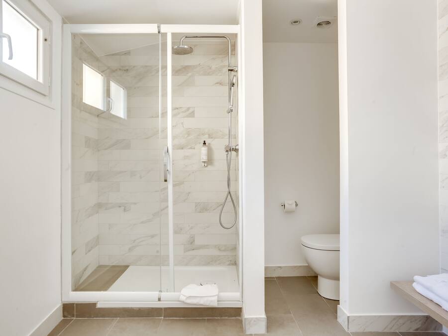 A modern bathroom with a glass-enclosed shower, a toilet, and a vanity with a towel rack.