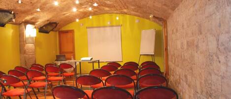 A conference room with red chairs, a whiteboard, and a laptop on a table.
