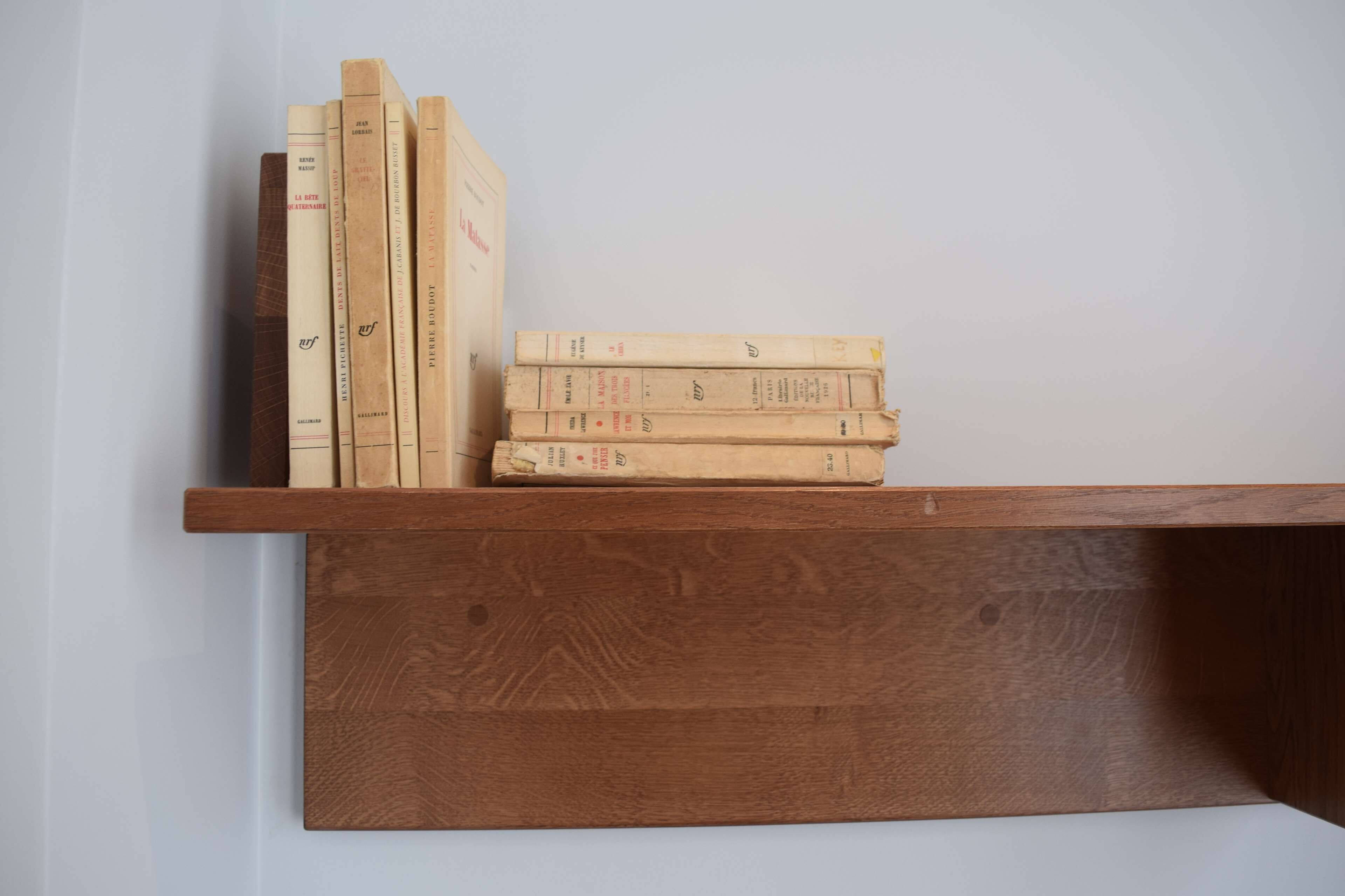 A wooden shelf with several books stacked on it.