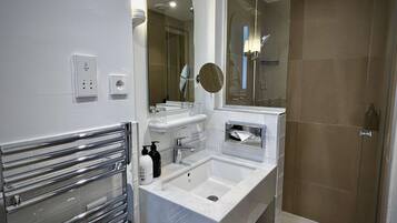 A modern bathroom with a vanity, mirror, and shower.