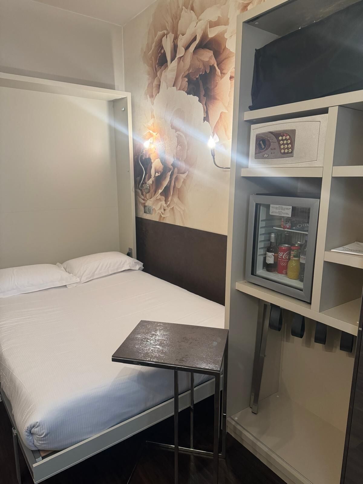 A compact hotel room with a single bed, a small table, a microwave, and a refrigerator.