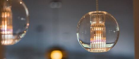 A close-up of a spherical pendant light with a visible filament inside, hanging from a ceiling.