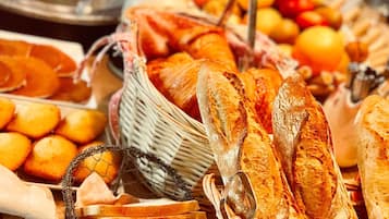 Diversos produtos de panificação, incluindo pão, pastelaria e bolos, expostos sobre uma mesa de madeira.