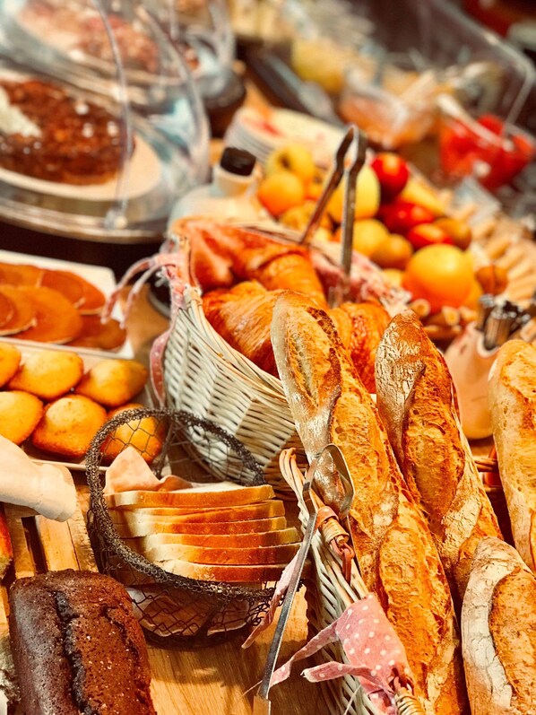 Diversa selección de productos horneados, como pan, pasteles y tortas, sobre una mesa de madera.