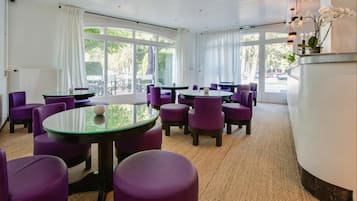 A hotel room with a large window, purple chairs, and a round table.