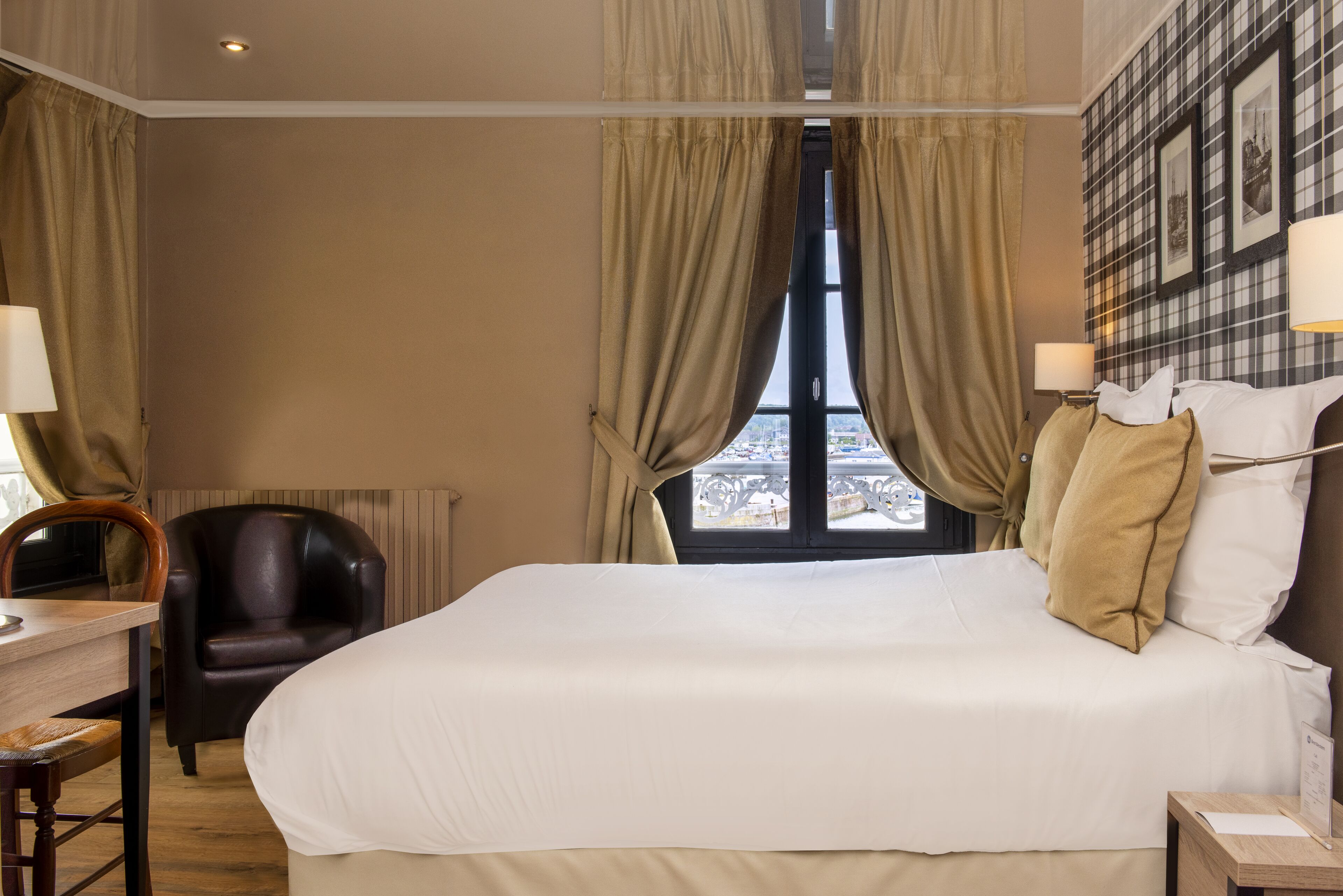 Una habitación de hotel con una cama grande, un escritorio con una silla y vistas a la ciudad desde la ventana.