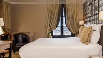 Una habitación de hotel con una cama grande, un escritorio con una silla y vistas a la ciudad desde la ventana.