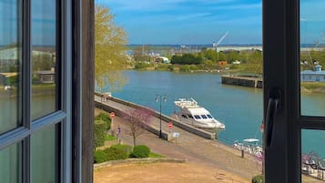 A view of a river with a boat docked on the right, a pedestrian bridge, and a clear sky.