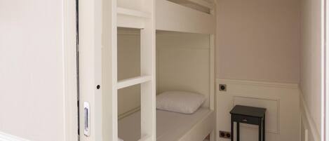 Dormitorio con literas, una mesita pequeña y una lámpara.