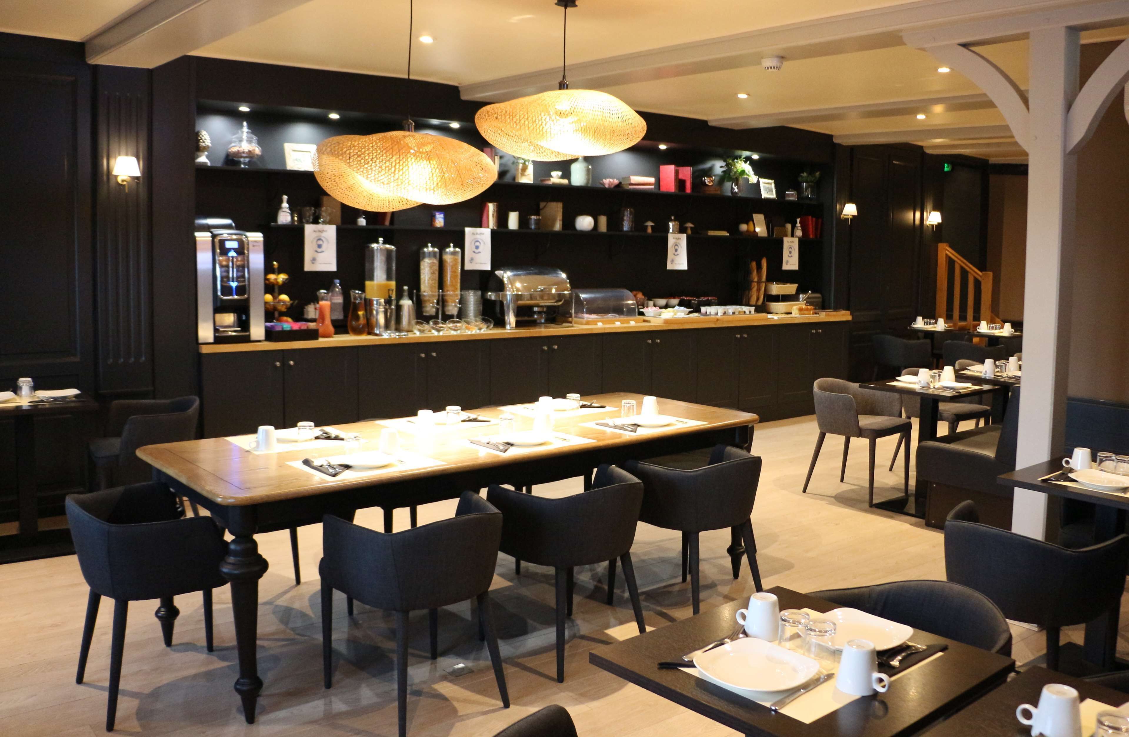 Un restaurant moderne doté d’une grande table conviviale, de cabines individuelles et d’un espace bar.