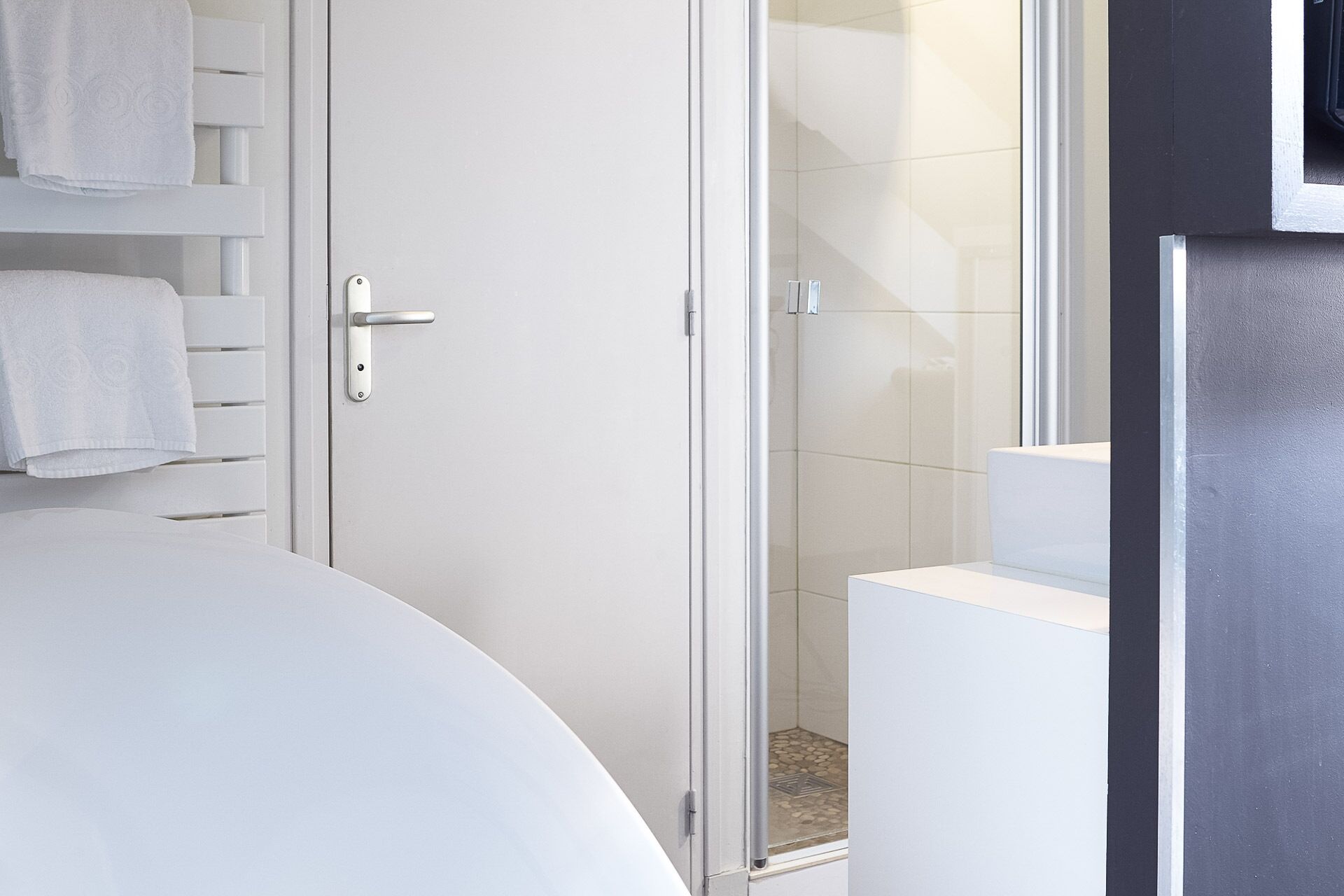 Een moderne badkamer met een douchecabine van glas, een wit toilet en een witte wastafel.