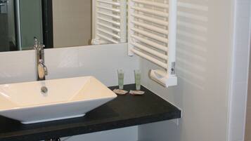 A bathroom with a white sink, black countertop, and a mirror above it.