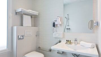 Un bagno moderno con il water bianco, un lavabo con uno specchio, un portasciugamani e una zona doccia.