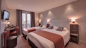Quarto de hotel com duas camas, uma mesa e uma televisão.