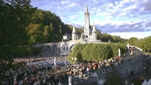 A large outdoor gathering in front of a historic building with a prominent tower. - Hôtel Alliance Lourdes (Lourdes)
