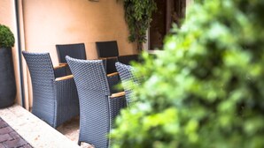An outdoor seating area with wicker chairs and a table, surrounded by a low wall and potted plants. - America Hotel Lourdes (Lourdes)