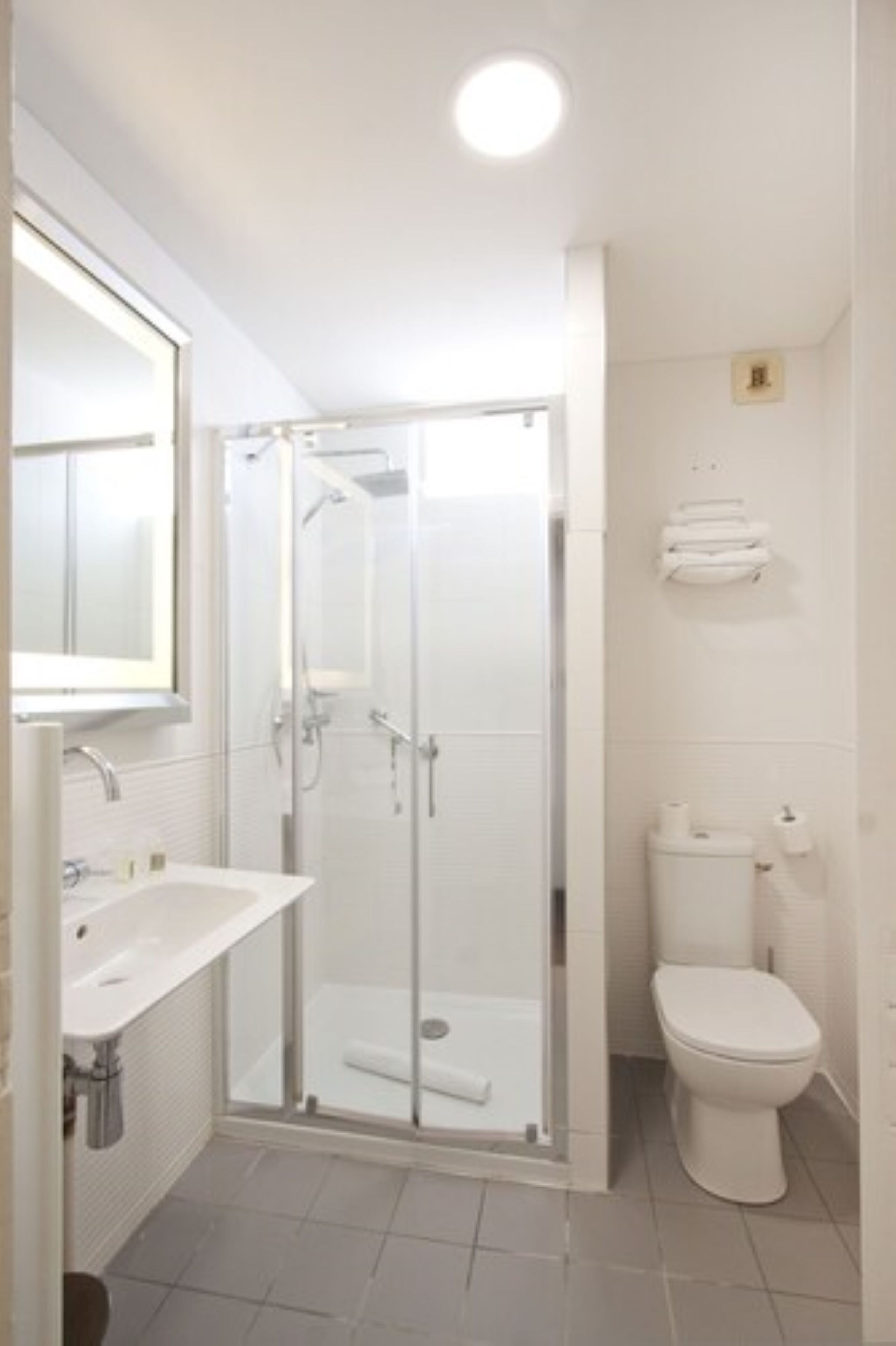 A bathroom with a glass-enclosed shower, a white sink, and a toilet.