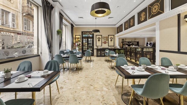 A restaurant with a marble floor, green chairs, and a black pendant light.