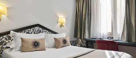 A neatly made bed with a headboard, two wall-mounted lamps, and a window with curtains.