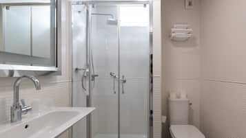 Une salle de bain moderne avec une douche à parois de verre, un lavabo blanc et des toilettes.