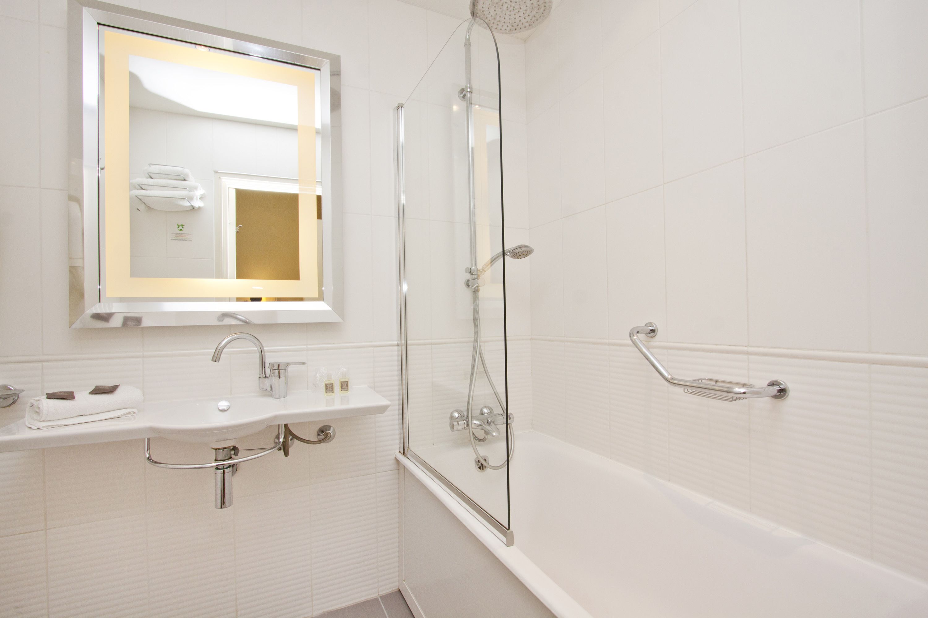 A modern bathroom with a glass-enclosed shower, a sink with a mirror, and a bathtub.
