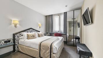 Una habitación de hotel con una cama grande, lámparas de noche, un escritorio y un espejo.