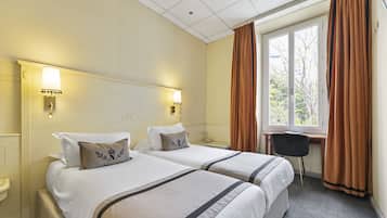 A hotel room with two beds, a desk, and a window with curtains.
