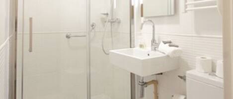 A modern bathroom with a glass shower enclosure, a white sink, and a toilet.