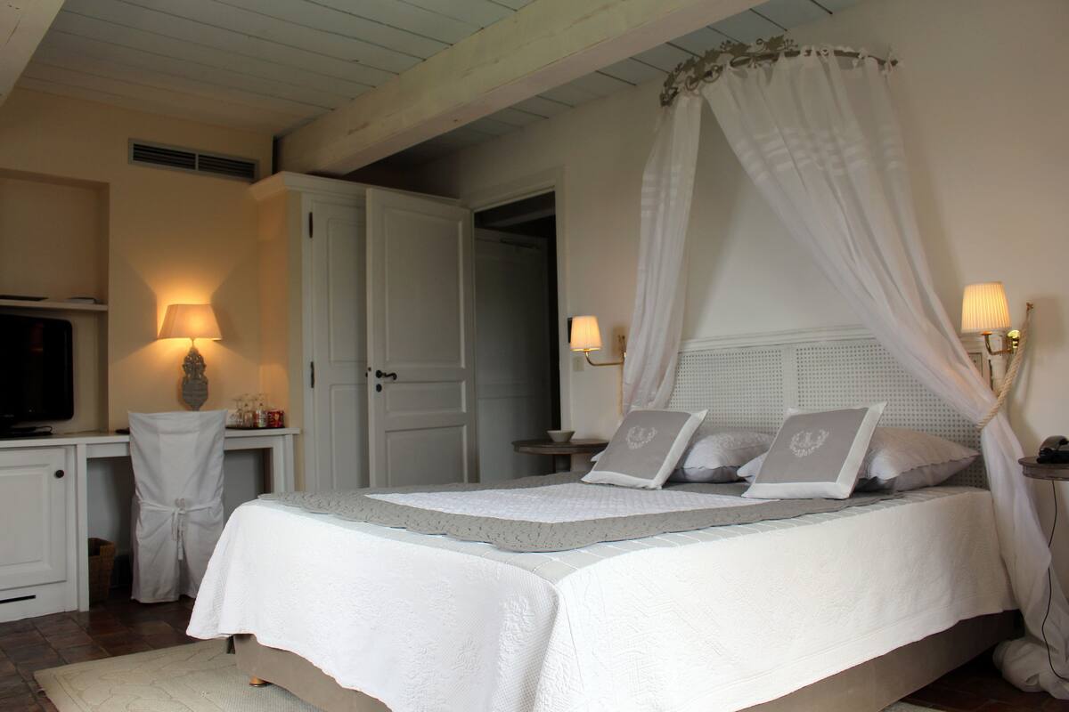 A bedroom with a bed, bedside lamps, a desk, and a chair.
