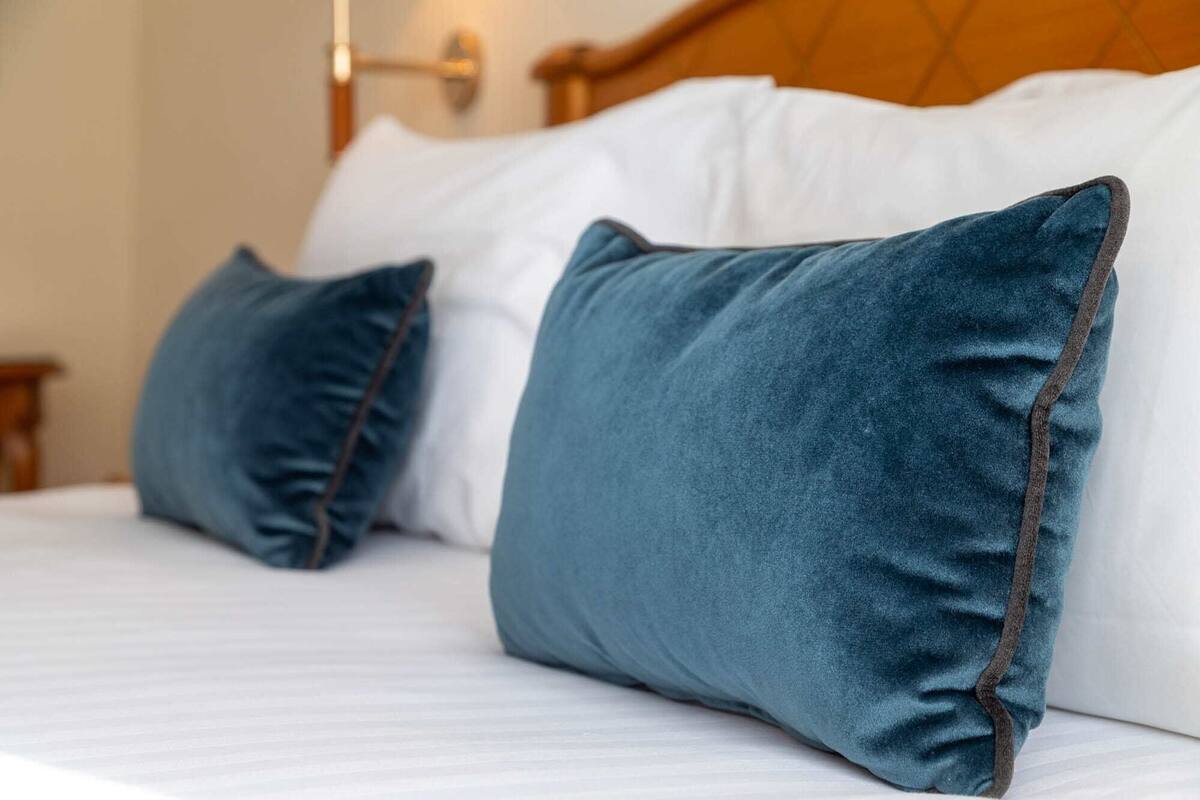 A bed with two pillows and a wooden headboard.