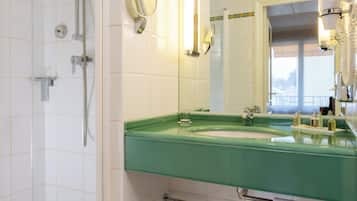 Un baño con bañera, ducha, lavabo verde y un espejo.