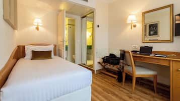 Una habitación de hotel con cama, escritorio, silla y espejo.