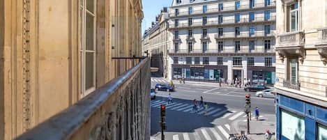 Vista de una calle con un edificio de estilo arquitectónico clásico, un paso de peatones y bicicletas estacionadas.