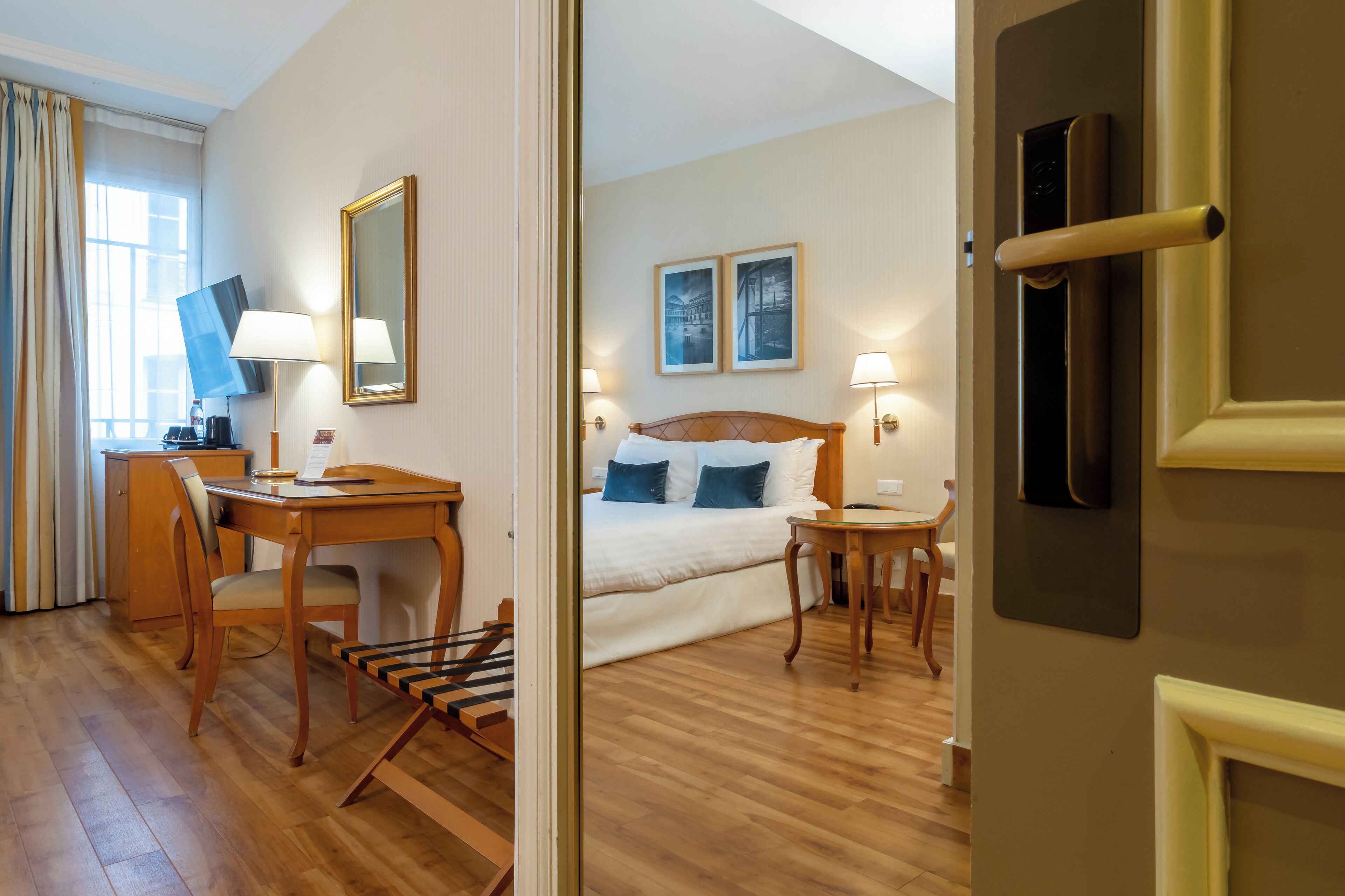 A hotel room with a bed, bedside tables, a desk with a chair, a TV, and a mirror.