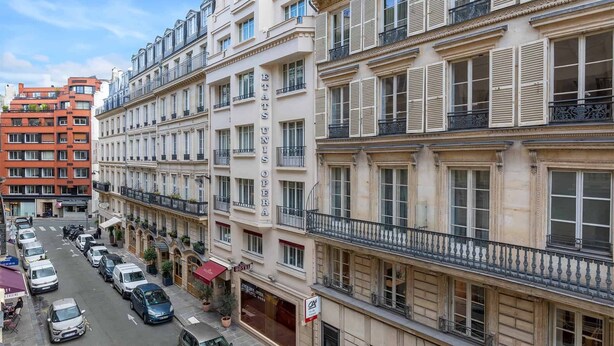 Un hotel de varios pisos con un estilo arquitectónico europeo clásico, que cuenta con balcones, ventanas amplias y una entrada central.