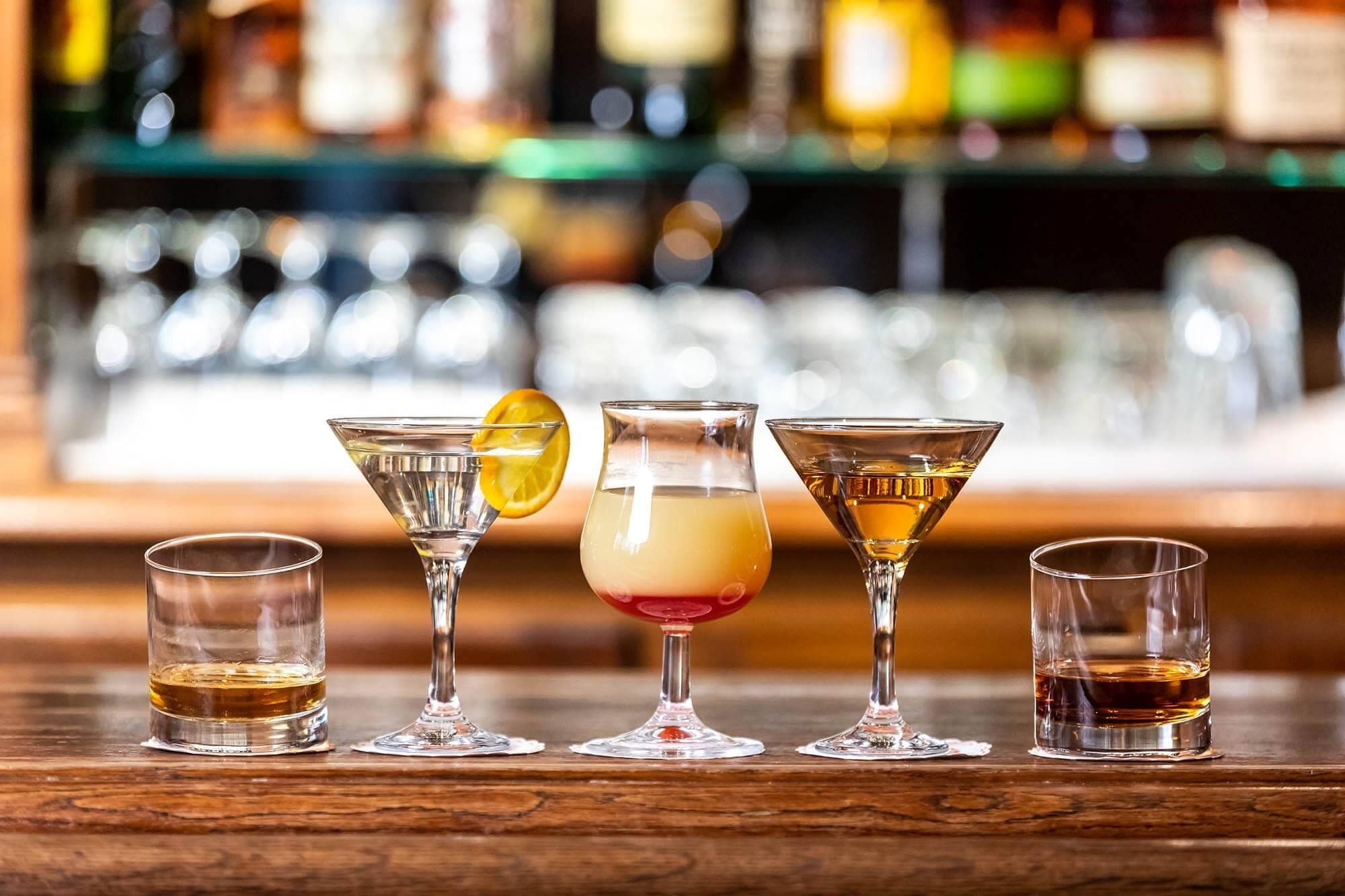 Un bar con varios vasos de distintas formas y tamaños, algunos conteniendo bebidas.