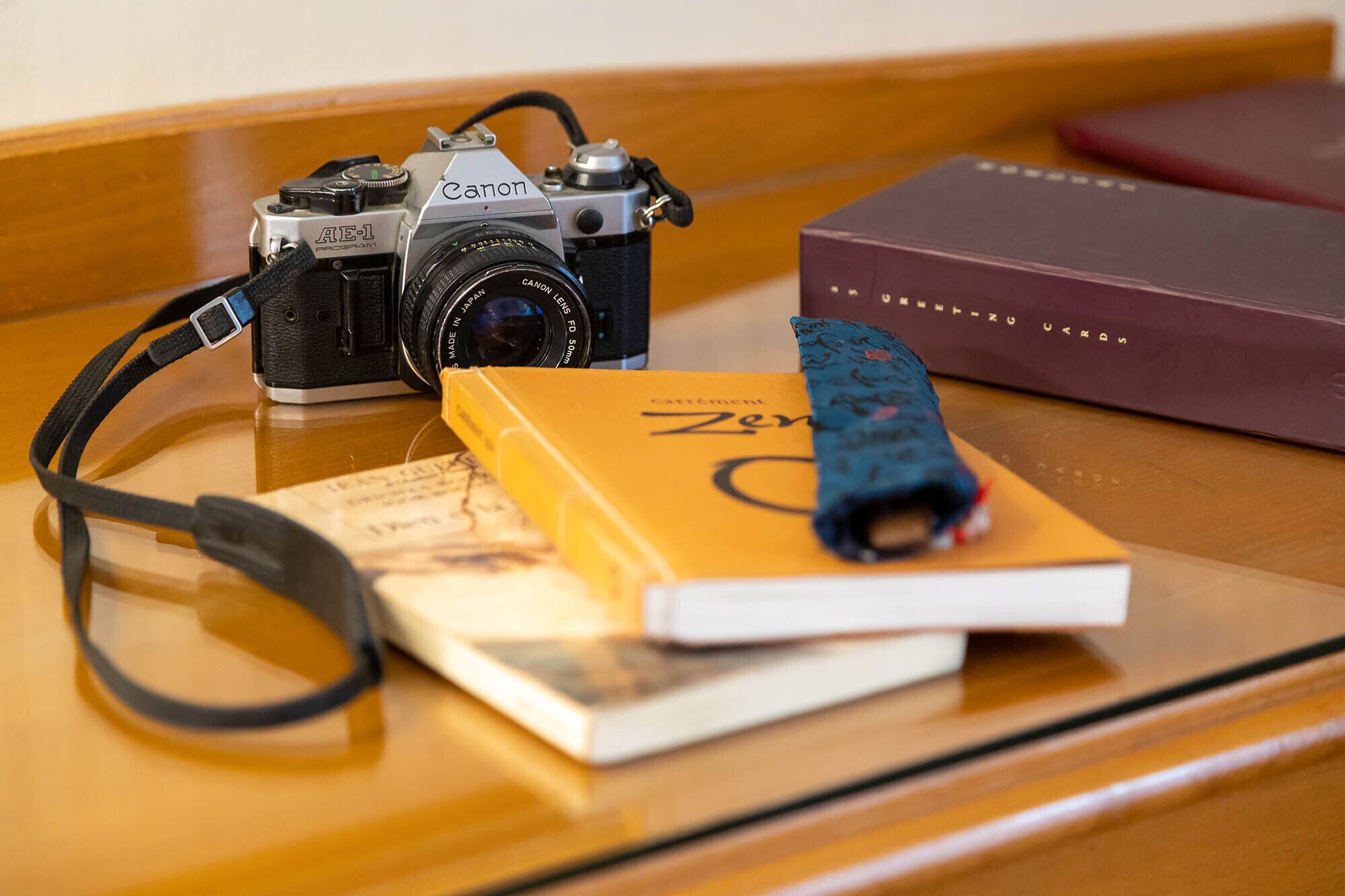 A camera, a book, and a notebook on a wooden surface.